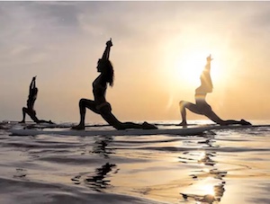 yoga on surfboard at sunset