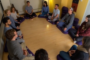 students sitting on floor in circle doing meditation